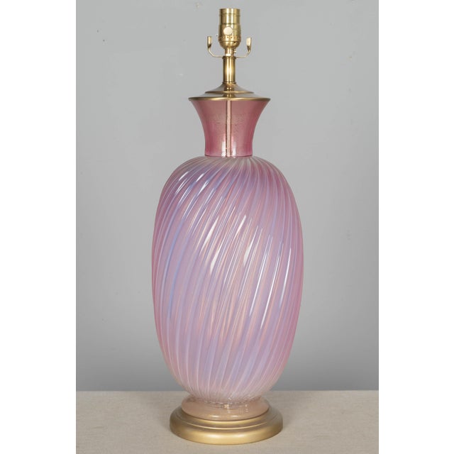 A Mid Century Murano glass lamp by Seguso with swirled ribbed form and large proportions. Hand-blown opalescent pink cased...