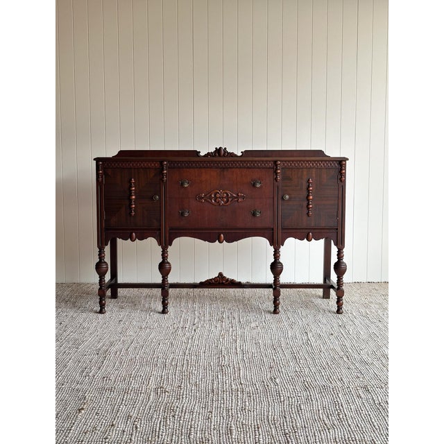 This sideboard credenza is crafted with book-matched, herringbone-veneered door panels and a solid carved apron and base....