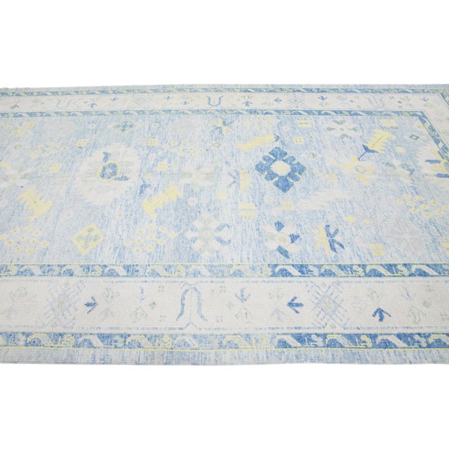 Beautiful modern Oushak hand-knotted wool rug with a light blue color field. This Turkish Piece has a gray frame with...