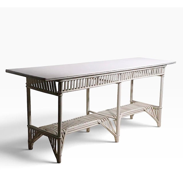 Unusually large split reed wicker console table in later white paint finish. The table is structurally sound and sturdy,...