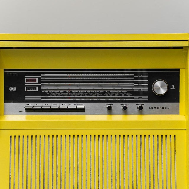 Radio cabinet. Yellow wooden frame with light brown legs. with a storage compartment. 1960s design. N.B.: The radio turns...