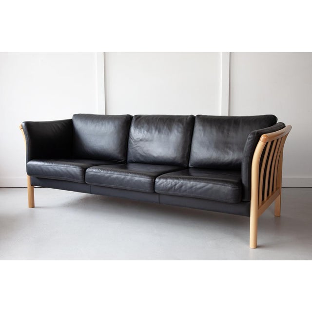 An elegant, black leather three-seater sofa, manufactured by Mogens Hansen, Stouby with a pleasing beech frame and quality...