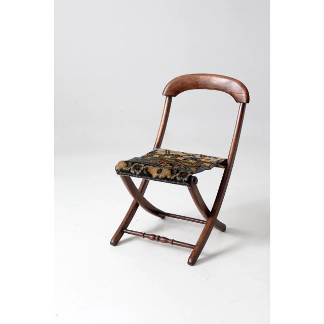 This late 19th century Victorian child's folding chair features a warm walnut frame, gently curved crest rail, turned...