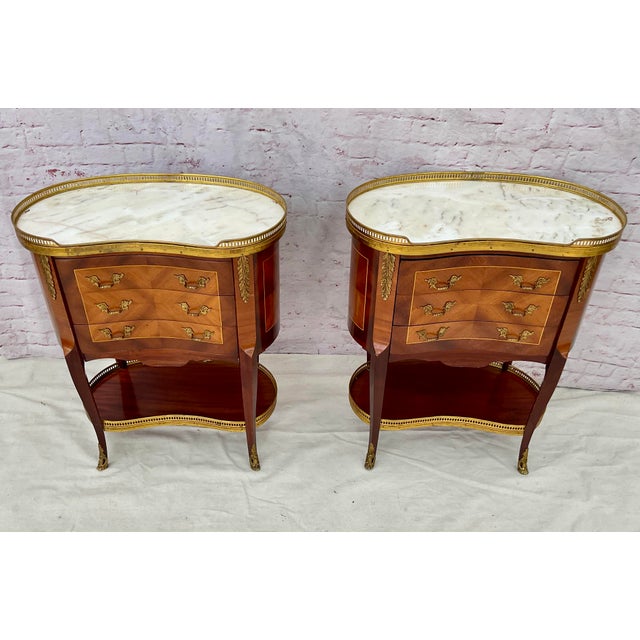 Elegant Pair of French Louis XV SIde Tables with Marble Tops. Each table features a bombe facade that flows seamlessly...