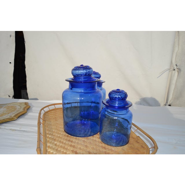 Set of three cobalt blue canister sets from the mid 20th century. Handblown with daisy lids. Two have small chips. This...