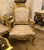 A stunning French Rococo-style armchair featuring luxurious beige damask upholstery and an elaborately carved wooden frame...