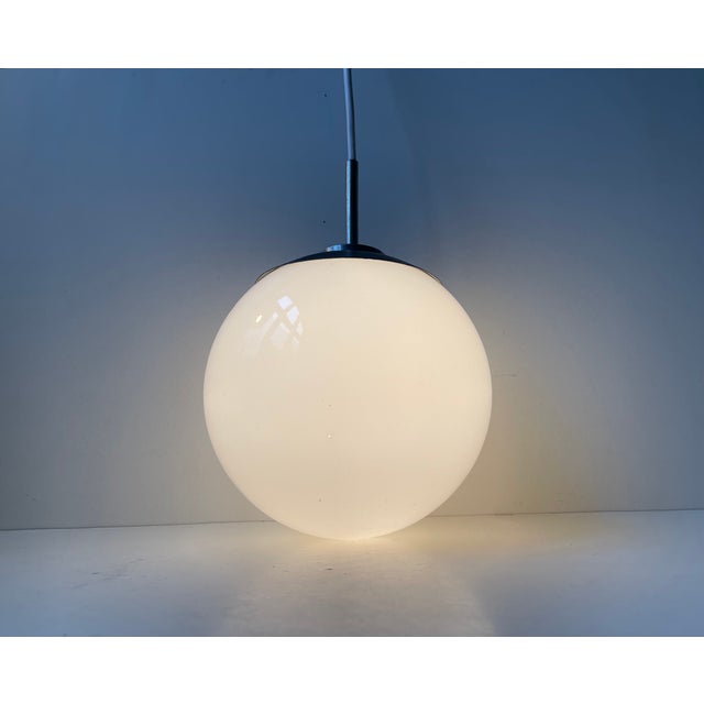 A white cased opaline glass and chrome/black paint plated steel pendant Light manufactured by Lyfa in Denmark during the...