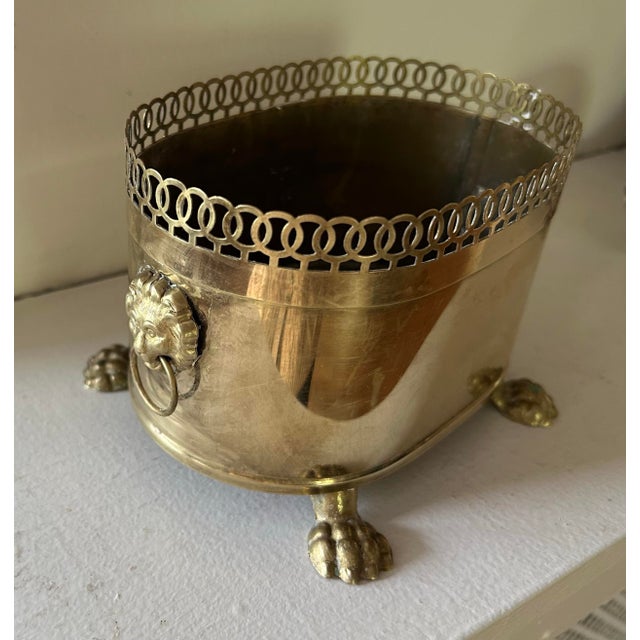 Vintage brass oval Jardinière with lion head handles, paw feet and filigree trim. The stamp on the bottom is "hand forged"...
