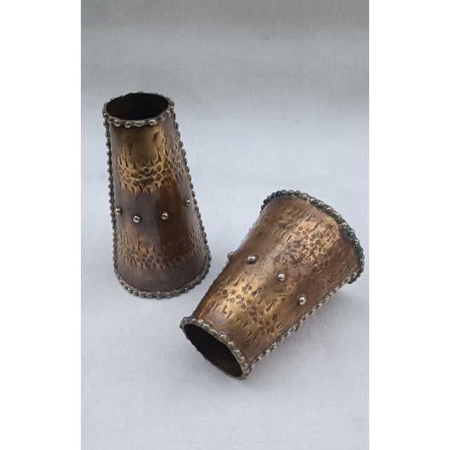Pair of cylindrical bronze vases with studs. Signed Cellini on the base. Italian manufacture. Various sizes. Tall vase:...