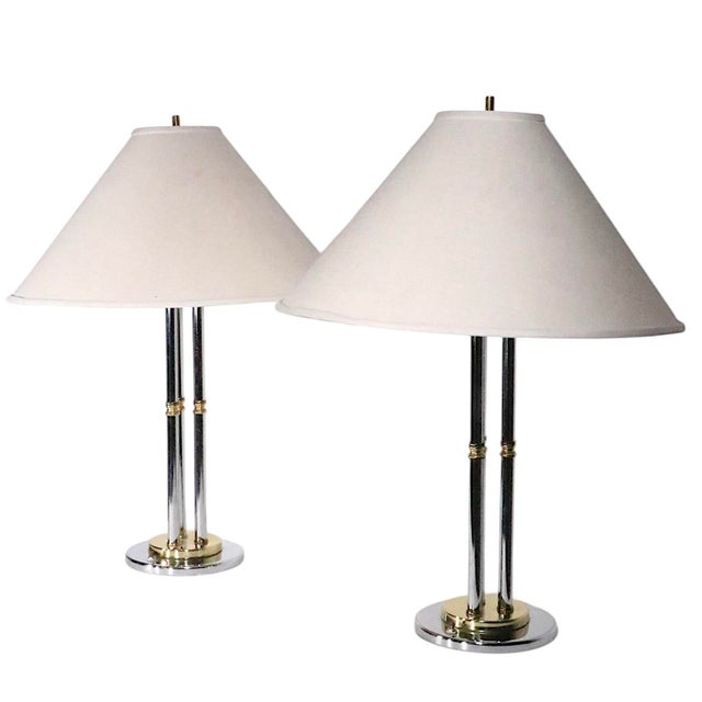 Chic pair of Post Modern, Hollywood Regency style table lamps, having three vertical chrome and brass rods mounted on a...