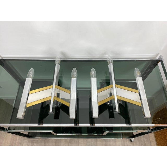 Geometric dynamic pair of sconces in a chrome structure and brass details, three lights each, by the Italian designer...