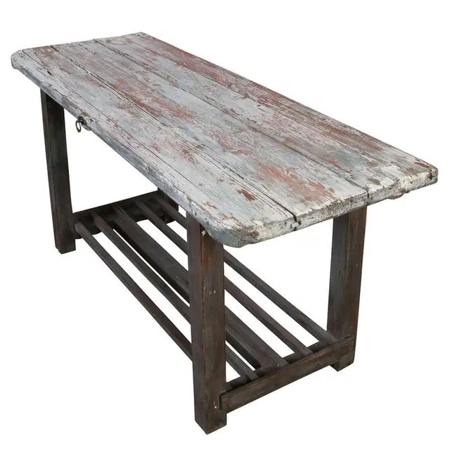 This rustic wood console table features a beautifully weathered patina with traces of original red and white paint, adding...
