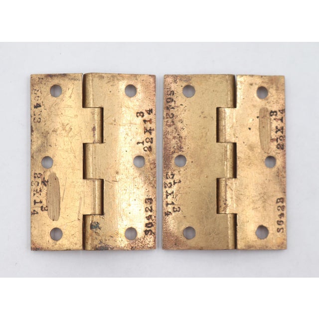 Vintage cabinet door hinges made of polished brass with flat tips, five knuckles, and a template hole pattern. The...