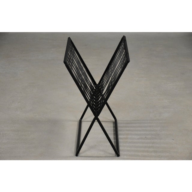 A mid century modern black iron and steel magazine rack in the style of Arthur Umanoff. 11.5” wide. 16.5” deep. 19” tall.