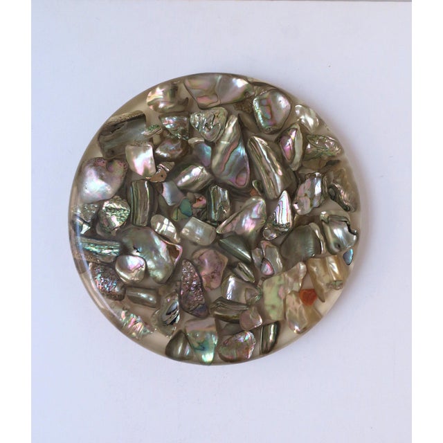 A Lucite acrylic and abalone seashell trivet, circa mid-20th century, 1960s, USA. Trivet is round with Lucite/acrylic...