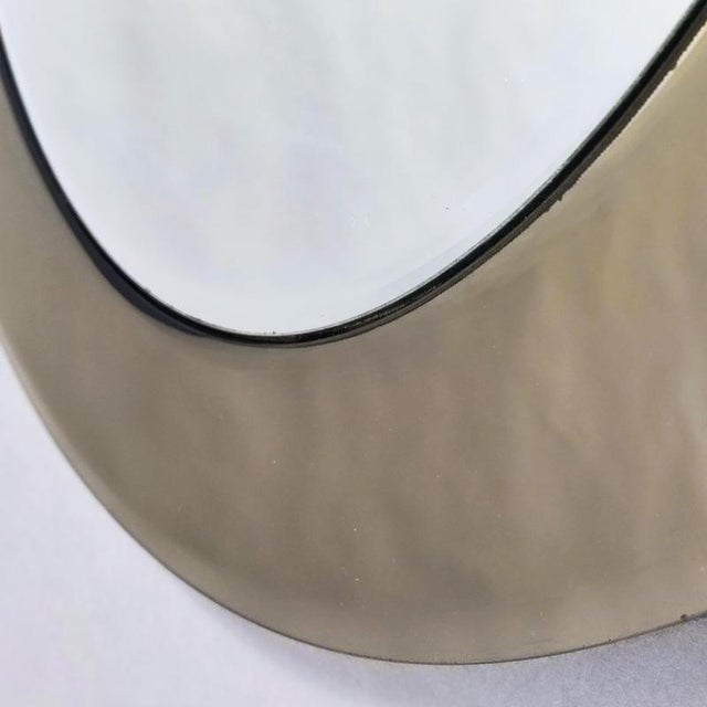 Round mirror by Rimadesio with a classic 1970s shape featuring two non-concentric circles. The mirror interior features a...