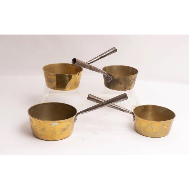 Four antique graduated brass hearth pans with iron riveted handles. The pans stack nicely like a set and the three...