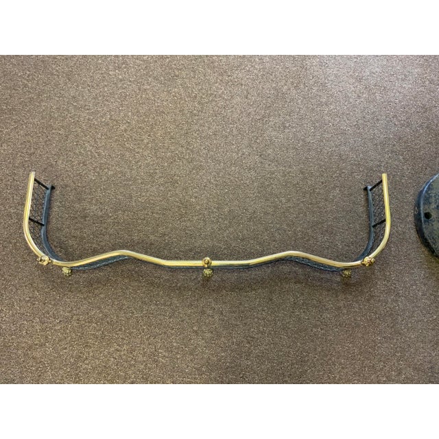 Mid 20th century. Metal and brass fireplace fender. Urn decor on the top edge, paw feet.