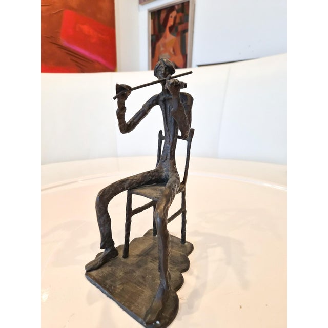 A brutalist styled, mid-century modern bronze violinist sculpture. This shows a figure holding a violin sitting on a...