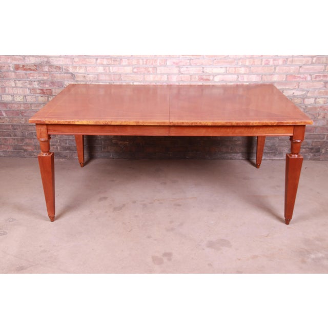 A beautiful Neoclassical style extension dining table By Baker Furniture USA, Circa 1990s Book-matched inlaid cherry wood,...