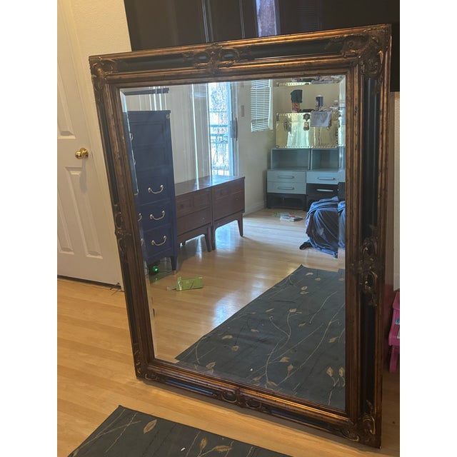 Exquisite ornate wall mirror with a gilded carved wood frame in a rich, antique gold finish. Intricate Baroque/Victorian-...