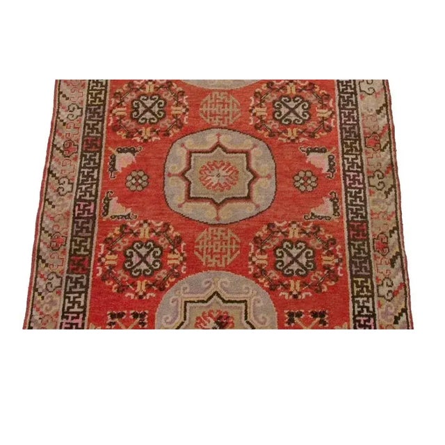 This antique Samarkand rug features a striking and structured composition centered around a series of repeating medallions...