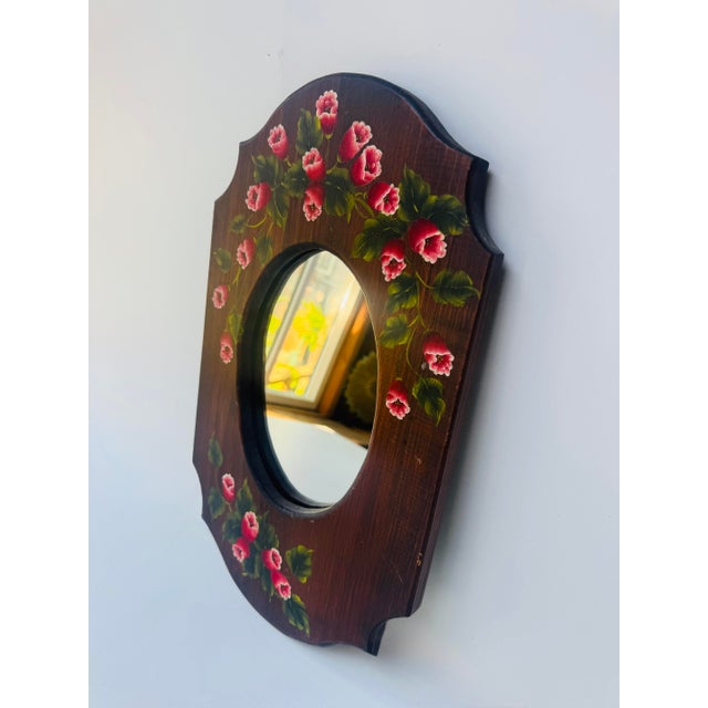 Vintage wall mirror with hand-painted pink flowers and green foliage on a dark stained wood frame. The shaped plaque-style...
