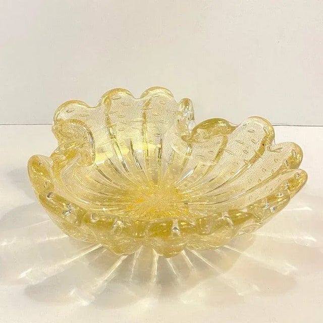 Midcentury, Murano-attributed, Italian, hand-blown, art glass clamshell dish or ashtray is embellished with gold flecks...