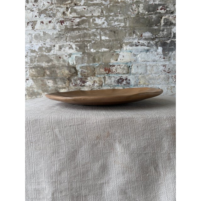 Handsome contemporary ceramic serving tray in a warm brown matte finish with softly irregular edges and a gently hand-...
