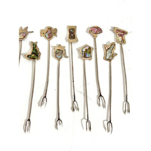 Striking and highly collectible, this vintage set of 11 cocktail picks features abstract organic toppers inlaid with...