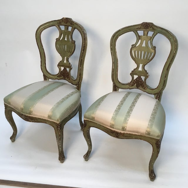 Charming pair of polychrome painted, carved and parcel gilt upholstered chairs. Beautiful color and patina. Upholstered in...
