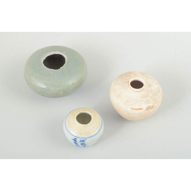 Korea, a set of three small vases in glazed tones, crafted in simple, curving forms. The vases vary in height and...