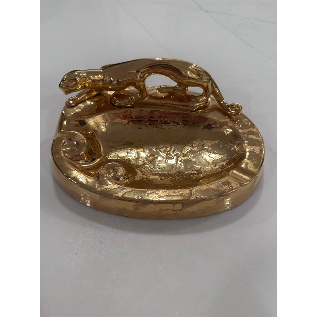 A glamorous vintage ceramic ashtray featuring a sculptural reclining panther finished in a richly textured weeping gold...