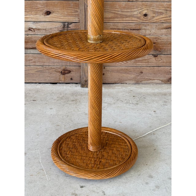 A sculptural Mid-20th Century coastal-style floor lamp featuring twisted rattan detailing and two round woven surfaces,...