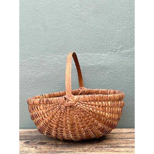 This vintage basket is a generous, gathering-style form with a broad, rounded body that swells gently from a shallow base...