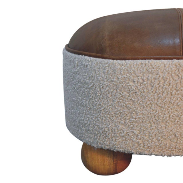 This round ottoman showcases a refined mix of textures, combining soft bouclé fabric with rich buffalo leather upholstery....