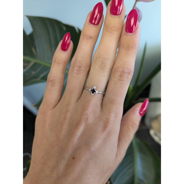 A natural black diamond anchors this solid 14K white gold ring in a bold asscher cut, surrounded by twelve white earth-...