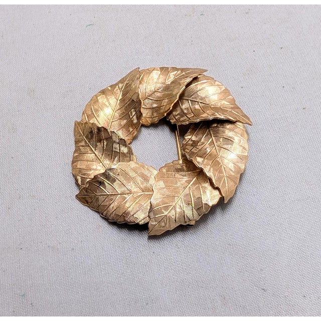 Mid 1950s to early 1960s goldtone textured overlapping leaves wreath brooch with security clasp. Marked "NAPIER©" on the...