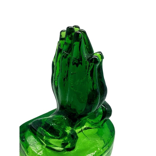 A striking mid-century style heavy pressed glass sculpture depicting praying hands in a vibrant emerald green hue. This...