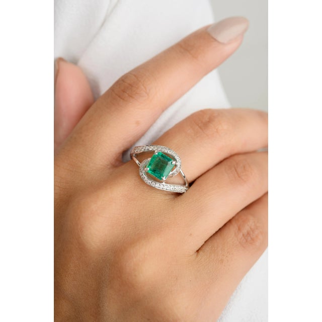 This stunning 18k white gold ring features a vibrant square-cut emerald as its centerpiece, beautifully accented by...