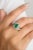 This stunning 18k white gold ring features a vibrant square-cut emerald as its centerpiece, beautifully accented by...