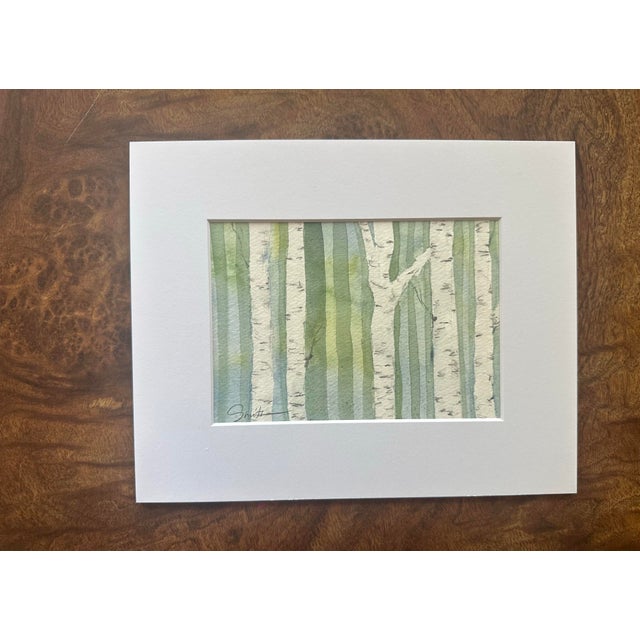 An original watercolor capturing the quiet beauty of a stand of slender birch trees. Soft washes of sage, eucalyptus, and...