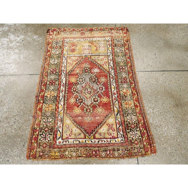 A vintage Turkish Anatolian throw rug. An abrashed red field is nearly filled by a rosette and carnation lozenge...