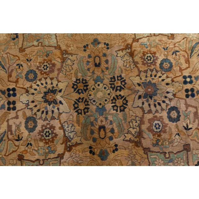 An early 20th century antique Kirman carpet from Persia, the peach field with an allover design of flowering palmettes and...