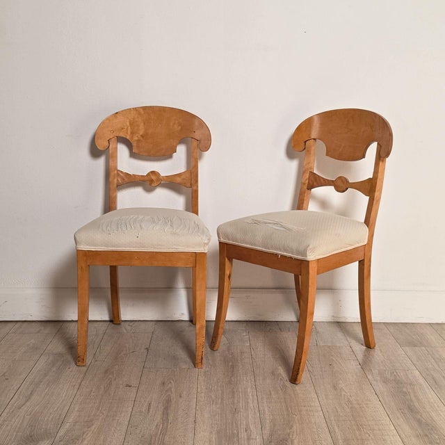 A pair of 19th-century shovelback Swedish Biedermeier side chairs in blonde birch wood. The chairs have the distinctive...