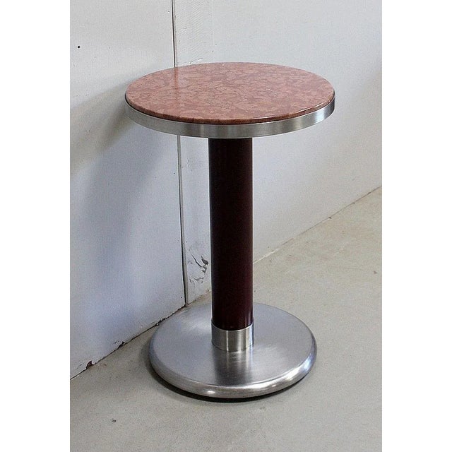 Small Circular Modern Pedestal Table, with cylindrical Iron shaft and Brushed Stainless Steel base. Its Top is composed or...