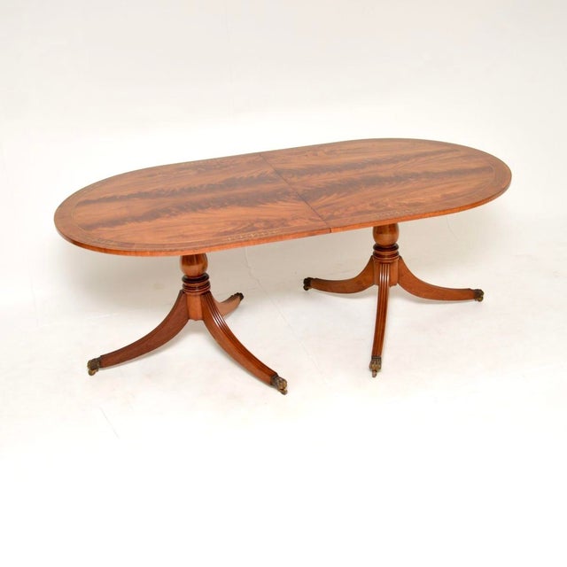 A large and impressive antique Regency style brass inlaid extending dining table. This was made in England, it dates from...