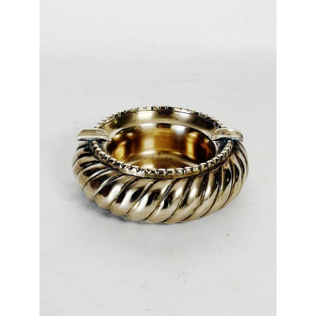 A 1950s French ashtray in solid brass, adorned with a sculpted, twisted design. Its generous circular shape is accentuated...