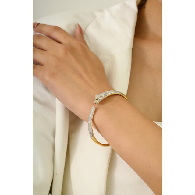 This striking open cuff bangle bracelet features a 2 round cut natural emeralds totaling 0.02 carats, and the diamonds...