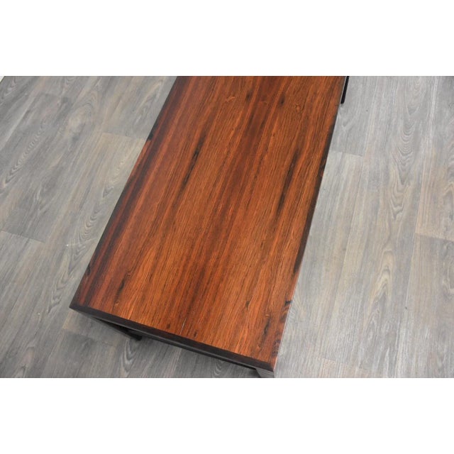 A rare mid century modern long rosewood coffee table or entryway bench with an ebonized base and single drawer with brass...